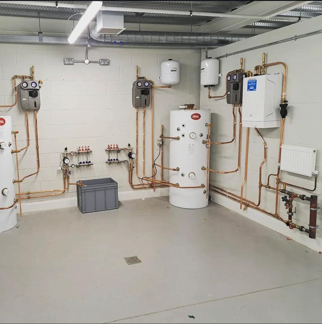 Plant room installation with hot water cylinders, boiler, manifolds and copper pipework