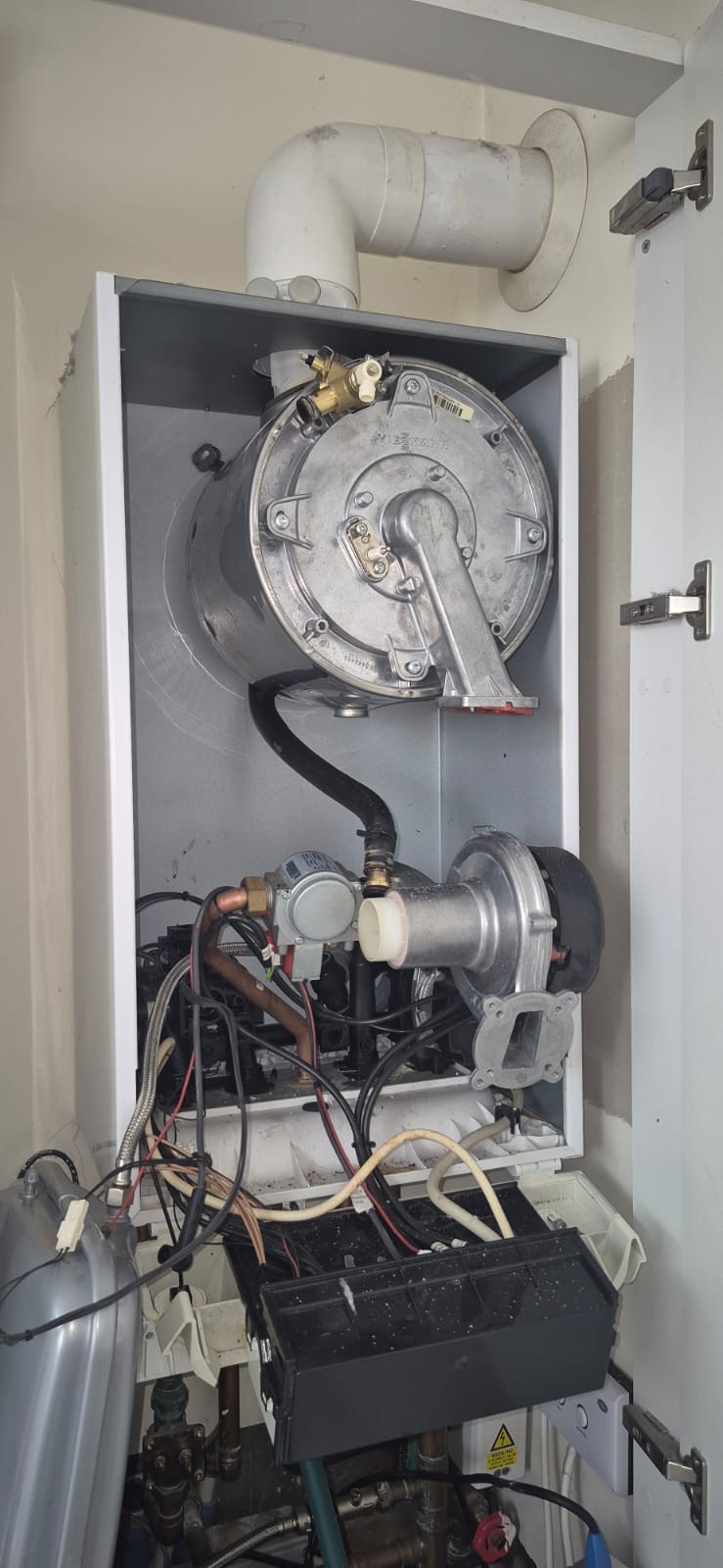 Gas boiler repair with the casing removed and the fan and burner accessible
