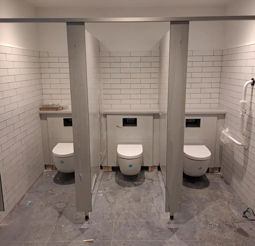 Bathroom plumbing with wall hung WCs and concealed cisterns in a tiled washroom