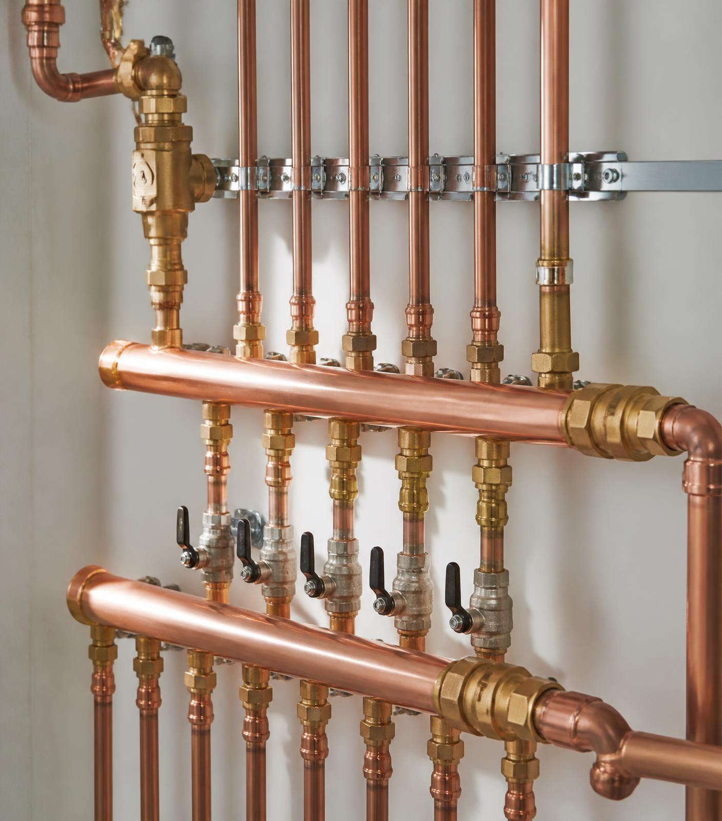Copper pipework and brass isolating valves installed on a utility room wall